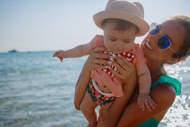 Mother holding her 6 months old baby at beach. Vacation concept